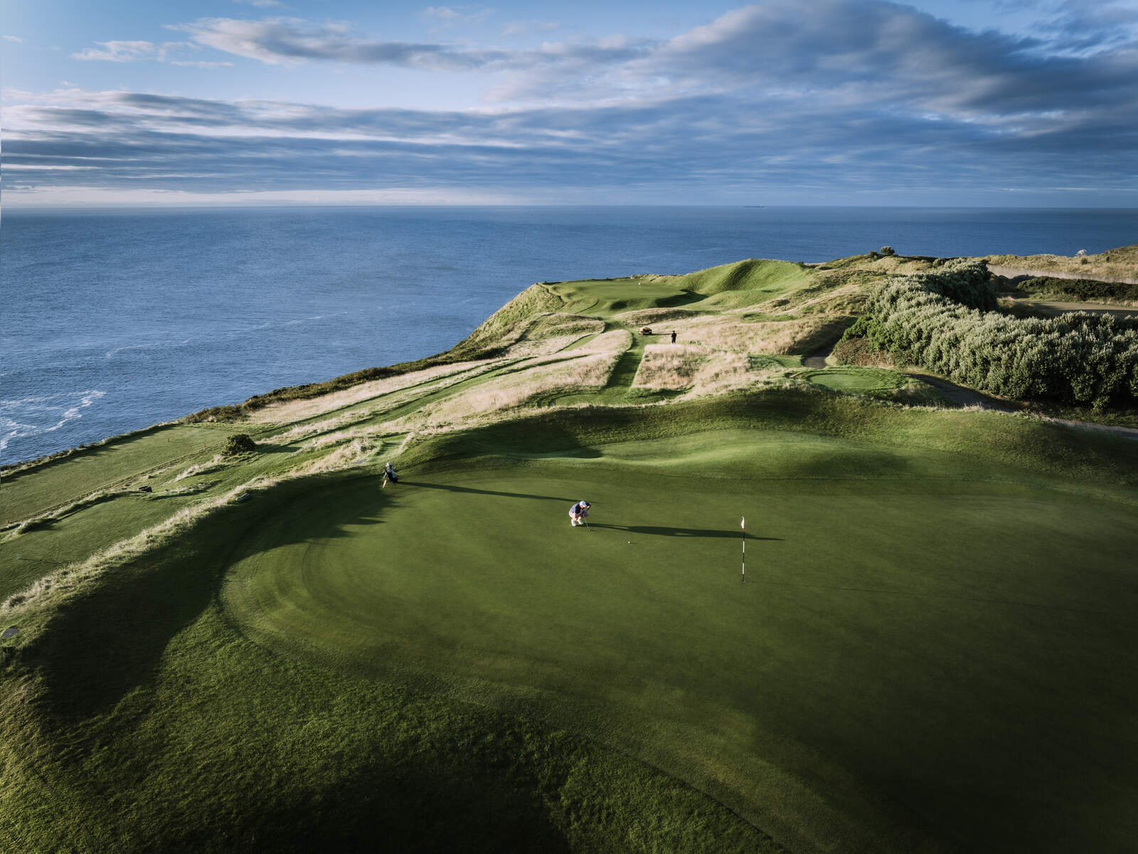 Golfers tee off at Hole 2, 'Gun Hole', Old Head Golf Links, Kinsale, Co. Cork, Ireland, overlooking ocean